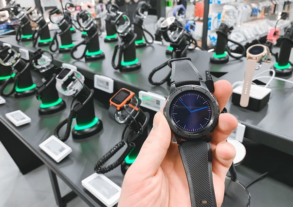 Man-in-the-electronics-store-holds a-smart-watch-in-his-hands
